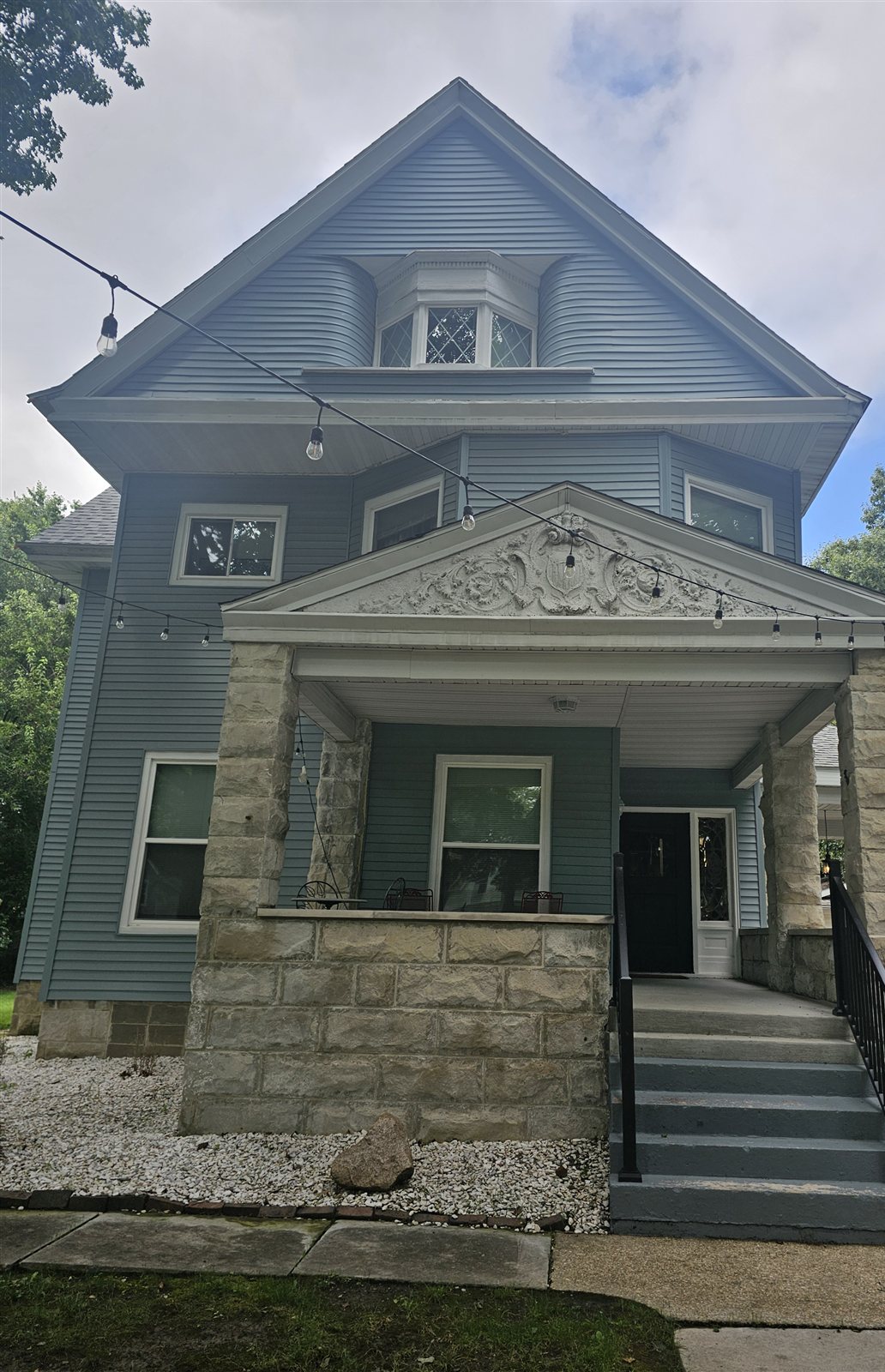 Front of the blue Victorian house at 157 N Douglas, Springfield, IL, with a covered stone porch, decorative gable, and steps